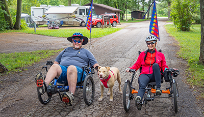 Two people on recumbent bikes with a dog