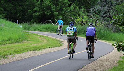 Biking along a paved trail surrounded by trees