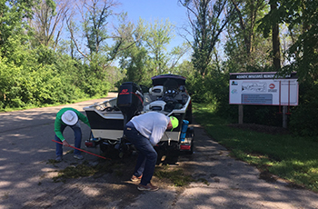 Boater inspecting and removing aquatic plants from their boat.